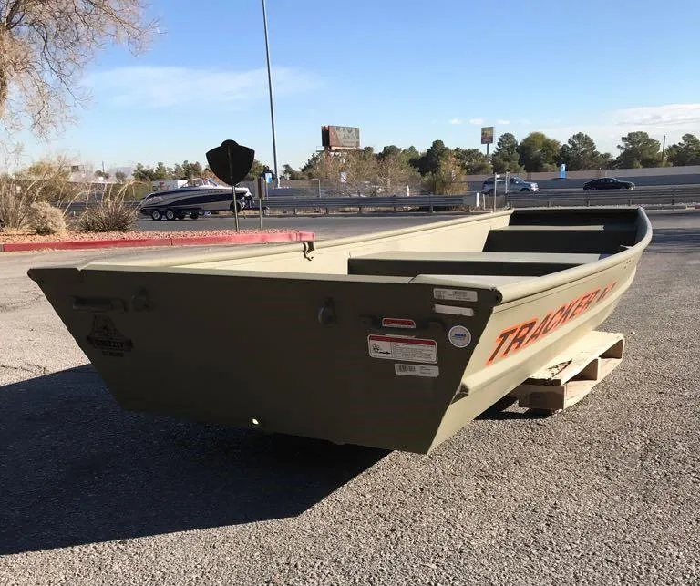 Slide: The Image of 2025 Tracker Grizzly 1236 Utility boat on pavement, sunny day. - 2