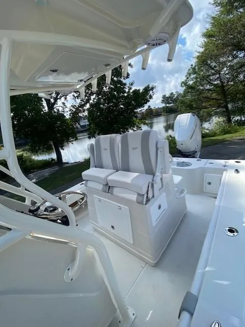 Slide: The Image of 2024 Ranger 2600 Bay boat interior with seating and console, near a scenic waterfront. - 8