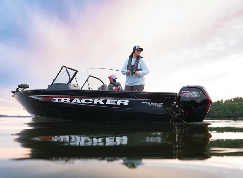 Slide: The Image of 2025 Tracker Pro Guide V-175 Combo boat on calm water, two people fishing. - 2