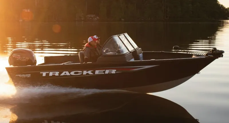 Slide: The Image of 2025 Tracker Pro Guide V-175 Combo boat cruising on a serene lake at sunset. - 3
