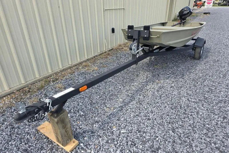 Slide: The Image of 2025 Tracker Grizzly 10 Jon boat on trailer, parked on gravel near a building. - 6