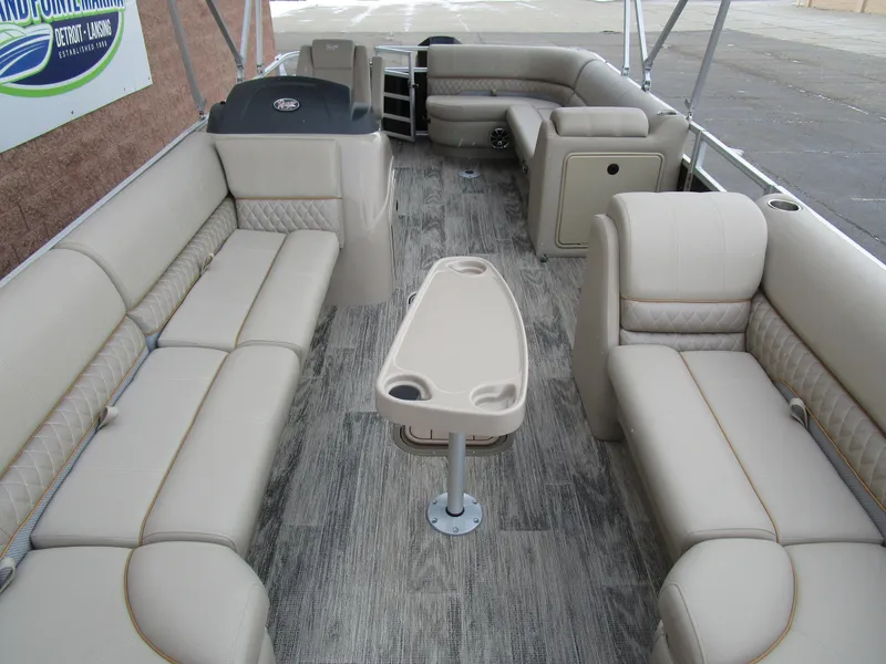 Slide: The Image of 2024 Ranger Reata 223C pontoon boat interior with beige seating and central table. - 10