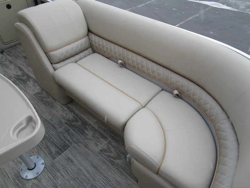 Slide: The Image of 2024 Ranger Reata 223C boat interior with beige cushioned seating and wood-patterned flooring. - 13