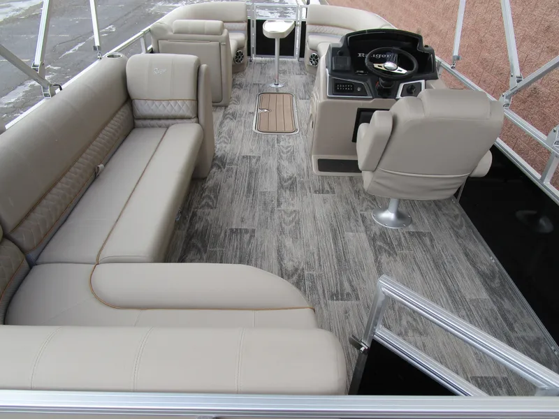 Slide: The Image of 2024 Ranger Reata 223C boat interior with beige seating and modern helm. - 17