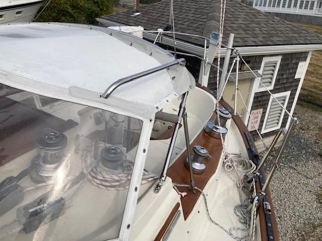 Slide: The Image of 1997 Pacific Seacraft 40 sailboat deck with winches and ropes, near a wooden building. - 11