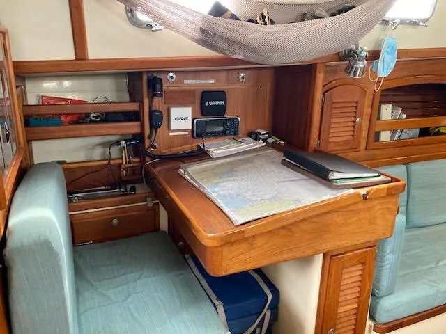 Slide: The Image of Navigation station inside a 1997 Pacific Seacraft 40 sailboat, featuring charts and communication equipment. - 26