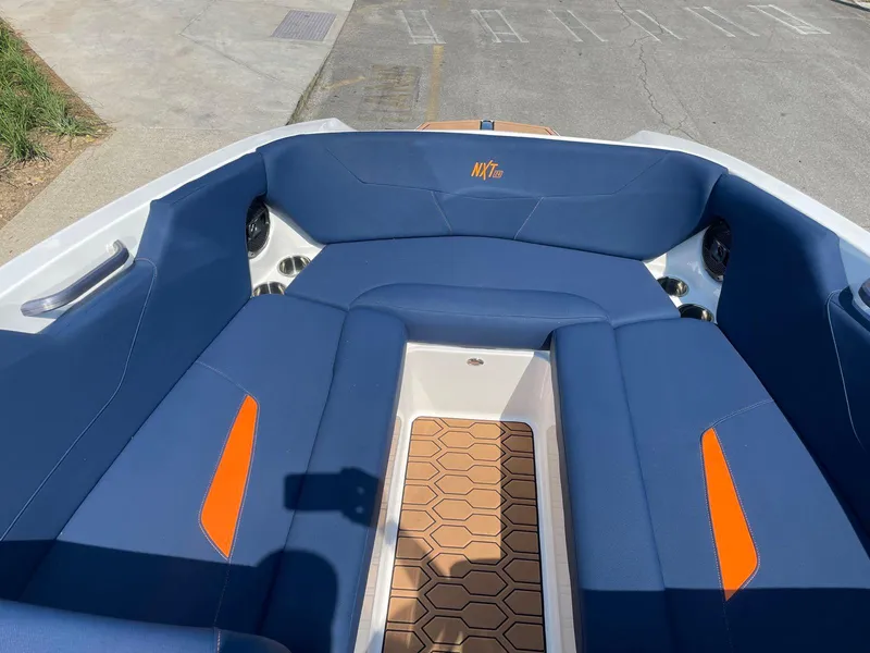 Slide: The Image of 2021 MasterCraft NXT 24 boat interior with blue and orange seating, hexagonal flooring. - 14