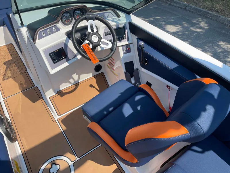 Slide: The Image of 2021 MasterCraft NXT 24 boat interior with blue and orange seating and modern dashboard. - 16