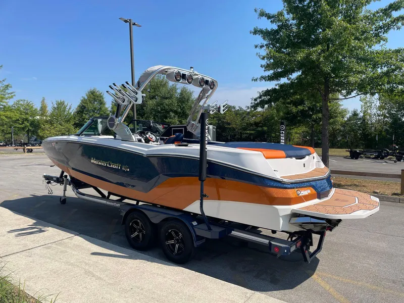 Slide: The Image of 2021 MasterCraft NXT 24 boat on trailer, parked outdoors, featuring sleek design and vibrant colors. - 4