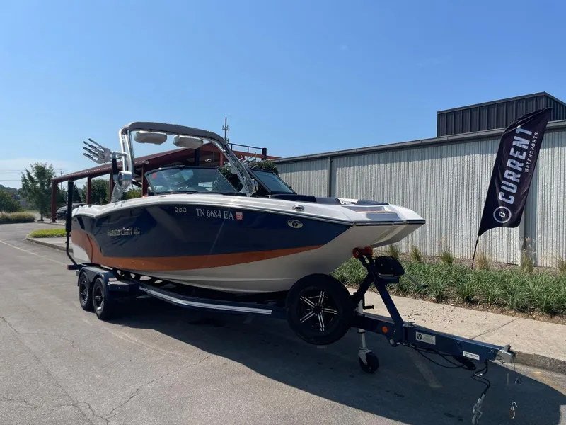 Slide: The Image of 2021 MasterCraft NXT 24 boat on trailer, parked outdoors near a building. - 6