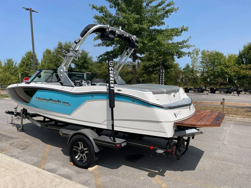 Slide: The Image of 2018 MasterCraft NXT20 boat on trailer, parked outdoors, with trees in the background. - 3