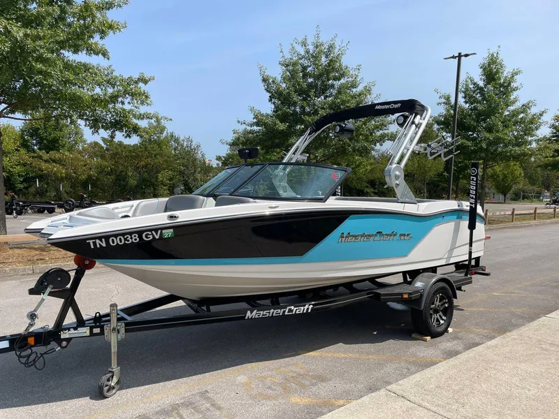 Slide: The Image of 2018 MasterCraft NXT20 boat on trailer, parked outdoors with trees in the background. - 4