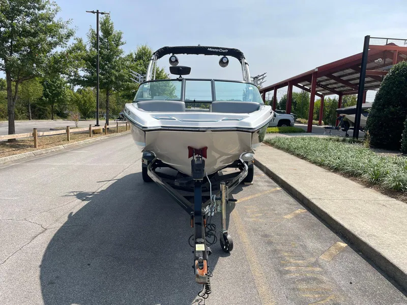 Slide: The Image of 2018 MasterCraft NXT20 boat on trailer, parked on a sunny street. - 6