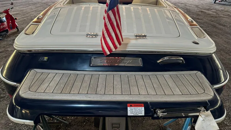 Slide: The Image of 2006 Chris-Craft Speedster boat with American flag, rear view in storage. - 12