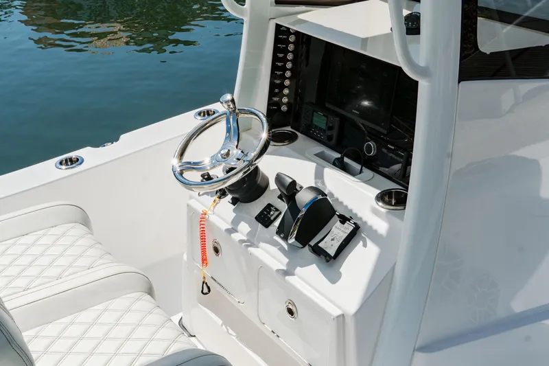 Slide: The Image of 2024 Blackwater 23 Hybrid boat cockpit with steering wheel and controls, featuring white quilted seating. - 19