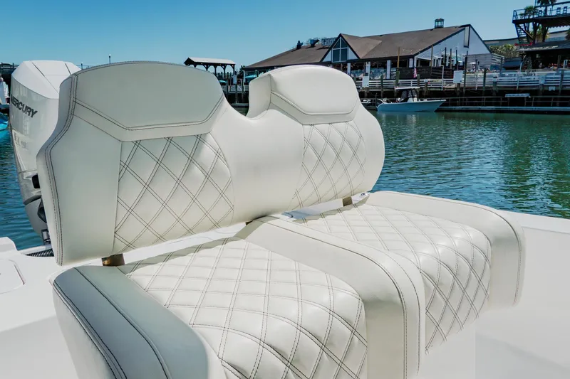 Slide: The Image of 2024 Blackwater 23 Hybrid boat with luxurious diamond-stitched seating, docked near waterfront buildings. - 27