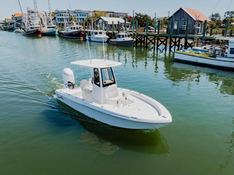 Slide: The Image of 2024 Blackwater 23 Hybrid boat cruising in a scenic harbor with docked vessels. - 6