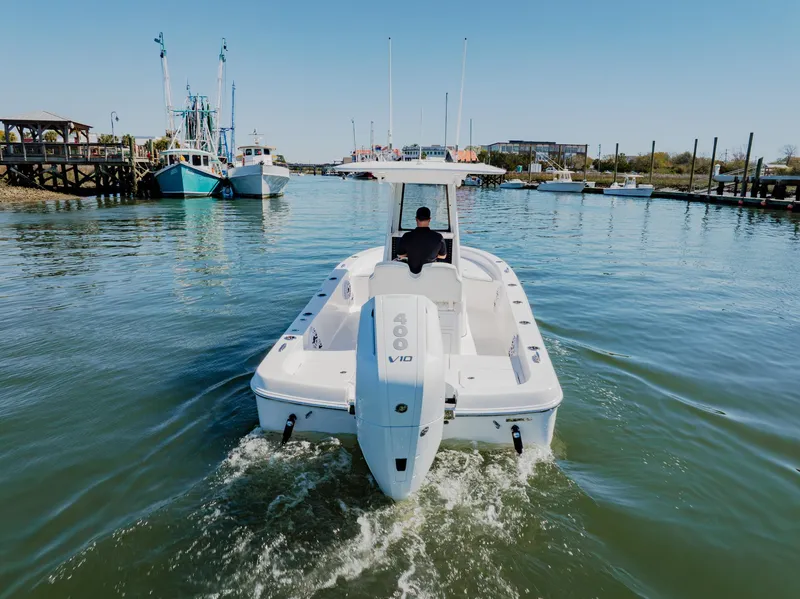 Slide: The Image of 2024 Blackwater 23 Hybrid boat navigating a calm marina, viewed from the rear. - 7