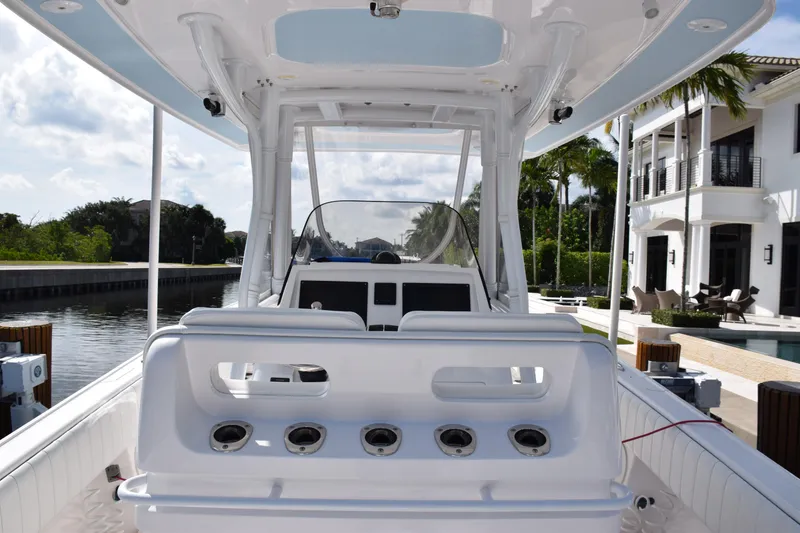 Slide: The Image of 2017 Intrepid 327 boat interior with rod holders, docked near luxury waterfront homes. - 35