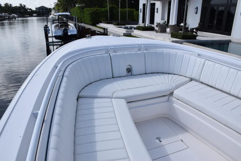 Slide: The Image of 2017 Intrepid 327 boat with white cushioned seating, docked by waterfront homes. - 7