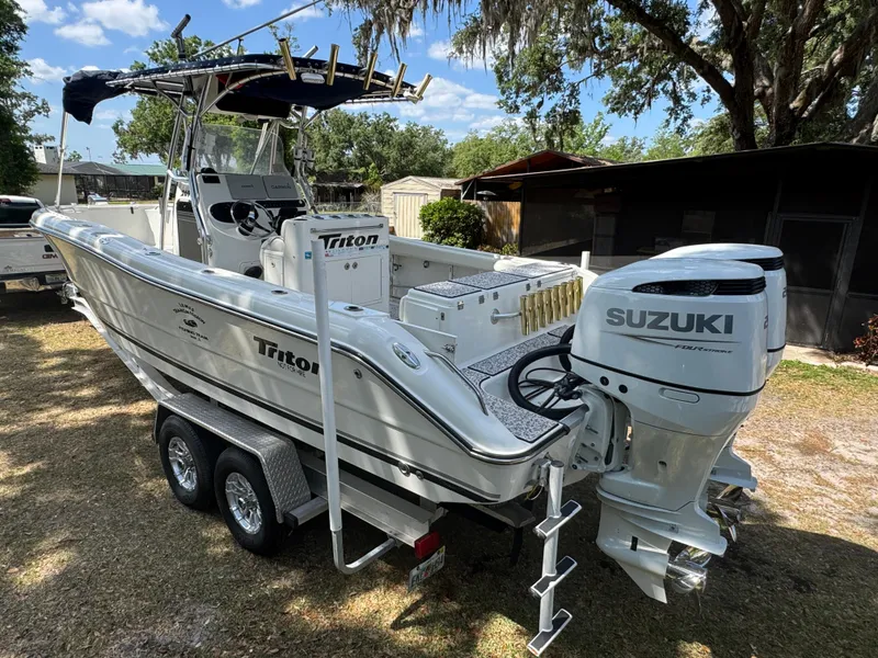 Slide: The Image of 2003 Triton 2690 CC boat with Suzuki outboard engine on a trailer, parked outdoors. - 11