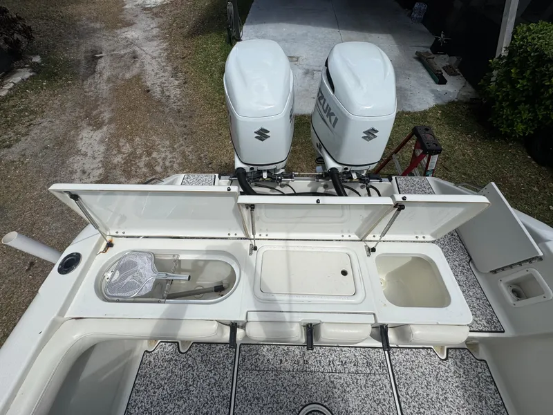 Slide: The Image of 2003 Triton 2690 CC boat with dual Suzuki outboard motors and open storage compartments. - 16