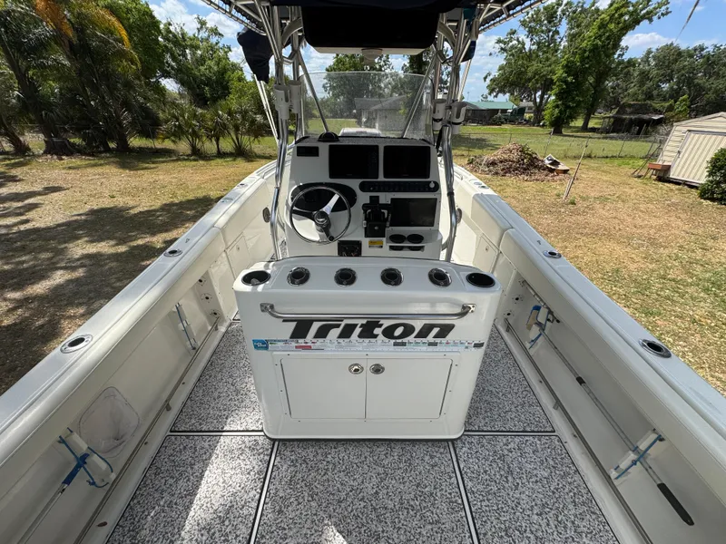 Slide: The Image of 2003 Triton 2690 CC boat interior with steering console and rod holders. - 19