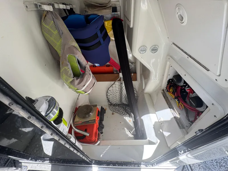 Slide: The Image of Storage compartment of 2003 Triton 2690 CC boat with life jackets and fishing gear. - 31