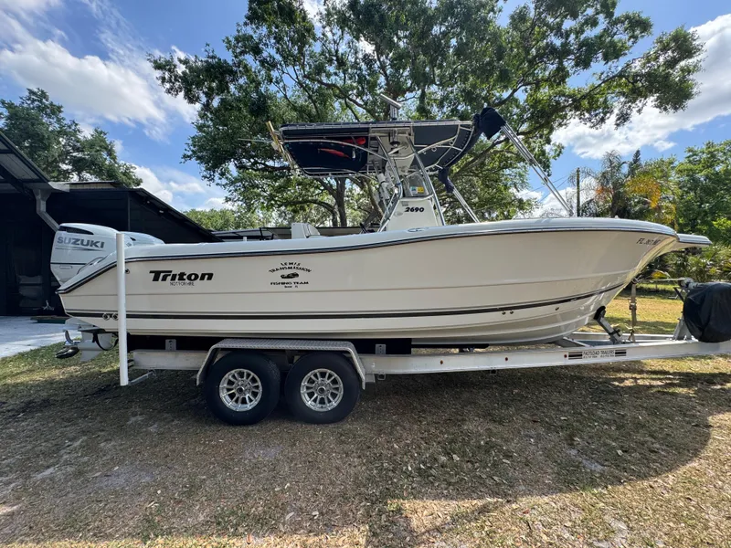 Slide: The Image of 2003 Triton 2690 CC boat on trailer, parked outdoors under trees. - 6