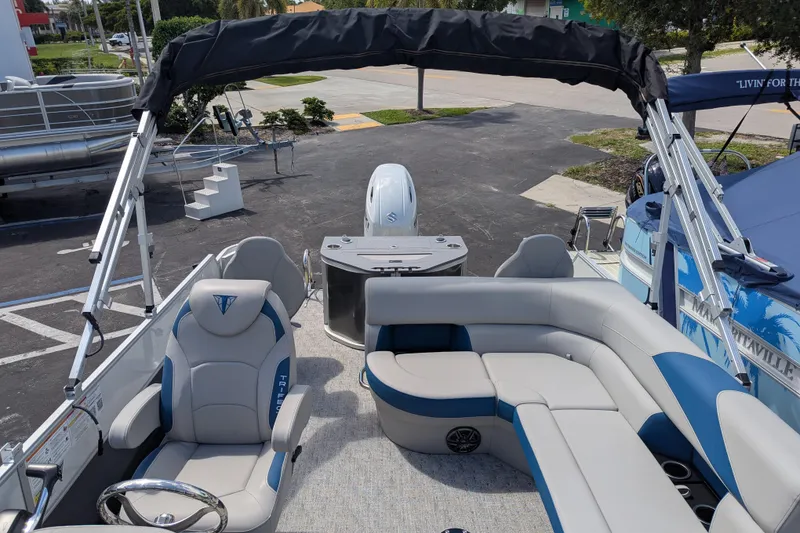 Slide: The Image of 2026 Trifecta 22TRFC LE pontoon boat interior with seating and helm, parked outdoors. - 10