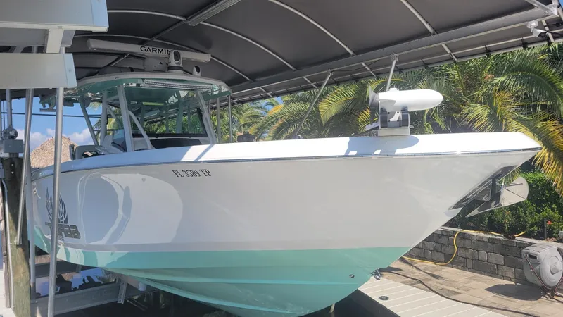 Slide: The Image of 2023 Wellcraft 352 Fisherman boat docked under a canopy with palm trees in the background. - 2