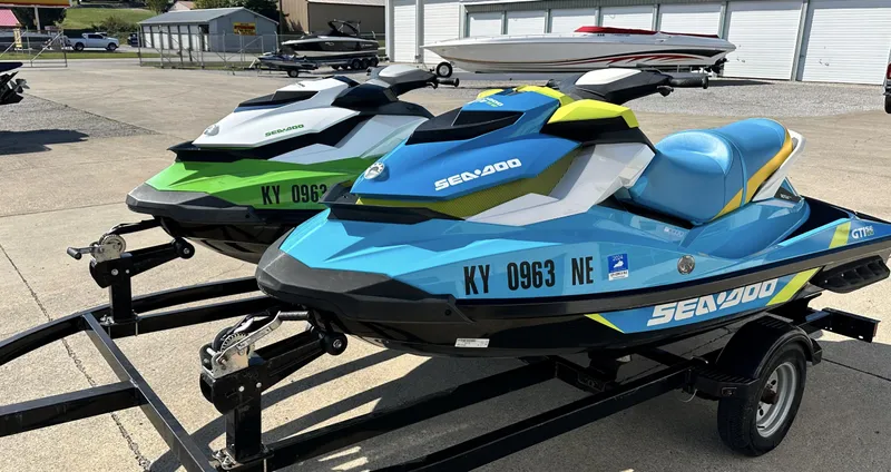 The Image of Two 2015 Sea-Doo GTI SE 130 jet skis on trailers, parked outdoors. - 0