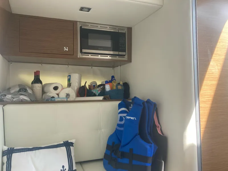 Slide: The Image of Interior of 2019 Cruisers Yachts 338 with microwave, life jackets, and storage items. - 17