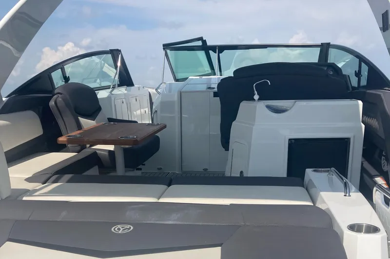 Slide: The Image of 2019 Cruisers Yachts 338 interior with seating, table, and helm under a clear sky. - 10