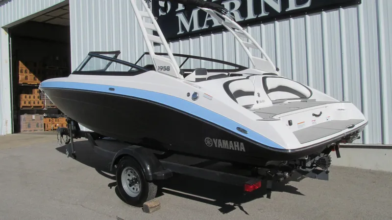 Slide: The Image of 2025 Yamaha Boats 195S on trailer outside marine shop. - 2