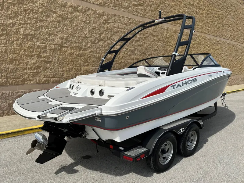 Slide: The Image of 2021 Tahoe 700 boat on trailer, sleek design, white and gray with red accents. - 2