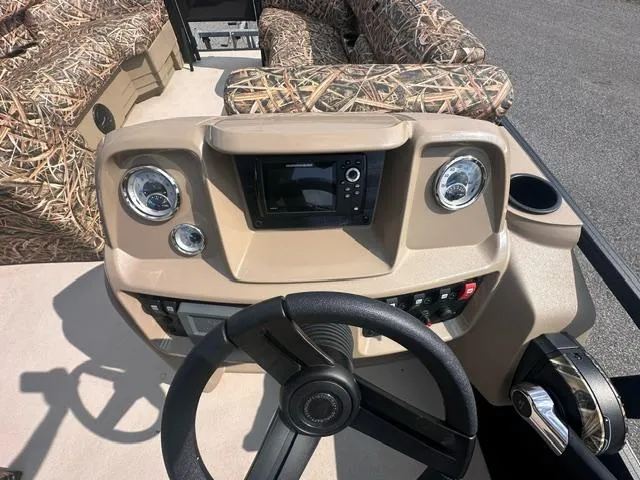 Slide: The Image of 2025 Starcraft LX 22 F boat dashboard with steering wheel and camo seating. - 6