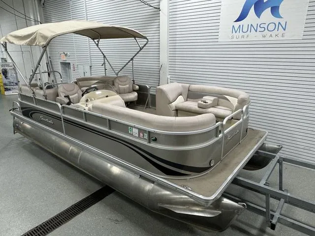 Slide: The Image of 2014 Sweetwater SW 2286 SLC pontoon boat in showroom, beige seating, Munson Surf Wake sign. - 19
