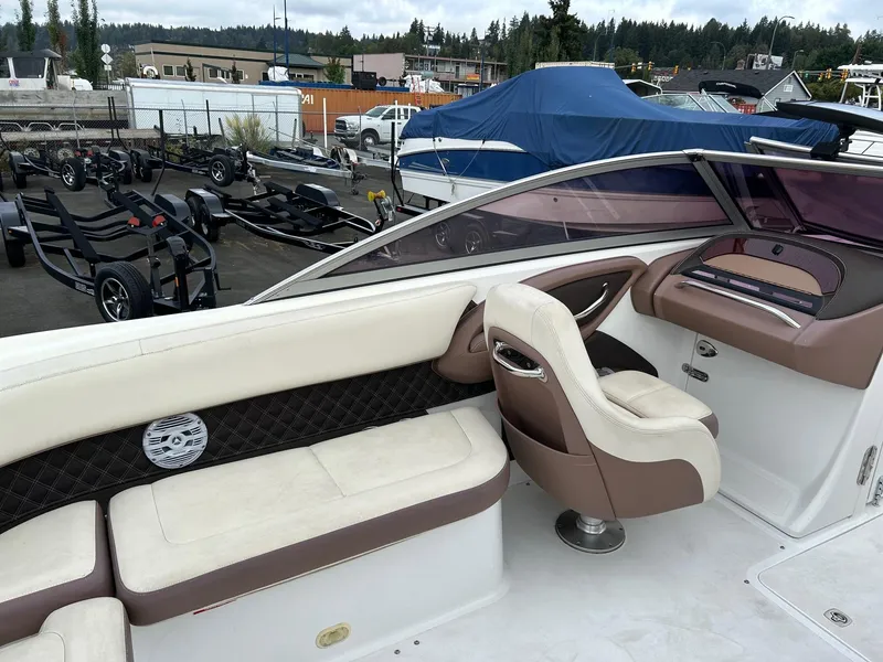 Slide: The Image of 2010 Cobalt 262 boat interior with beige seating and dashboard, parked in a marina. - 11