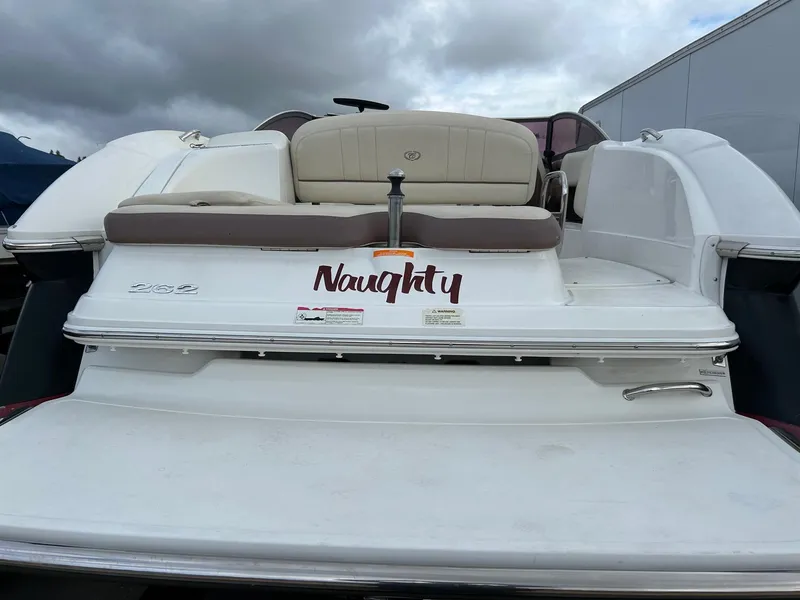 Slide: The Image of 2010 Cobalt 262 boat with "Naughty" decal on the stern, under cloudy skies. - 13