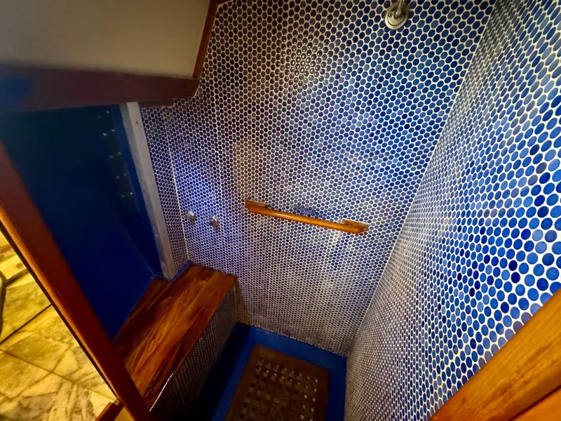 Slide: The Image of Shower area in 1983 Tayana 52 Aft Cockpit yacht with blue mosaic tiles and wooden accents. - 14