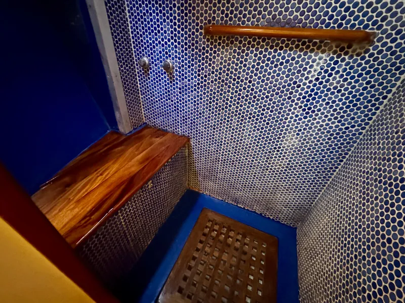 Slide: The Image of Shower area in 1983 Tayana 52 Aft Cockpit yacht with wooden bench and blue mosaic tiles. - 15