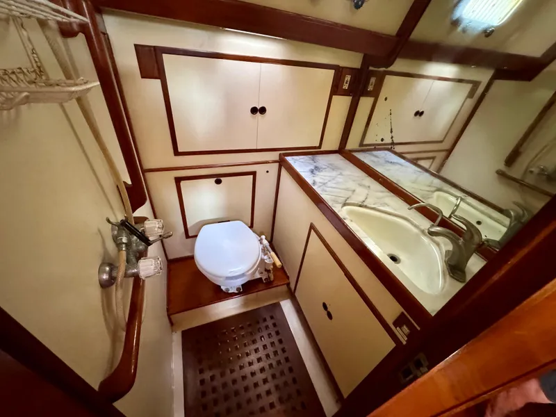 Slide: The Image of 1983 Tayana 52 Aft Cockpit yacht bathroom with sink, toilet, and wooden cabinetry. - 23