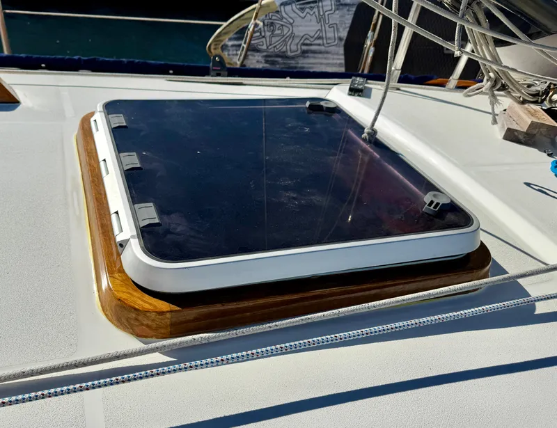 Slide: The Image of Hatch on 1983 Tayana 52 Aft Cockpit sailboat deck, featuring wooden trim and metal fittings. - 44