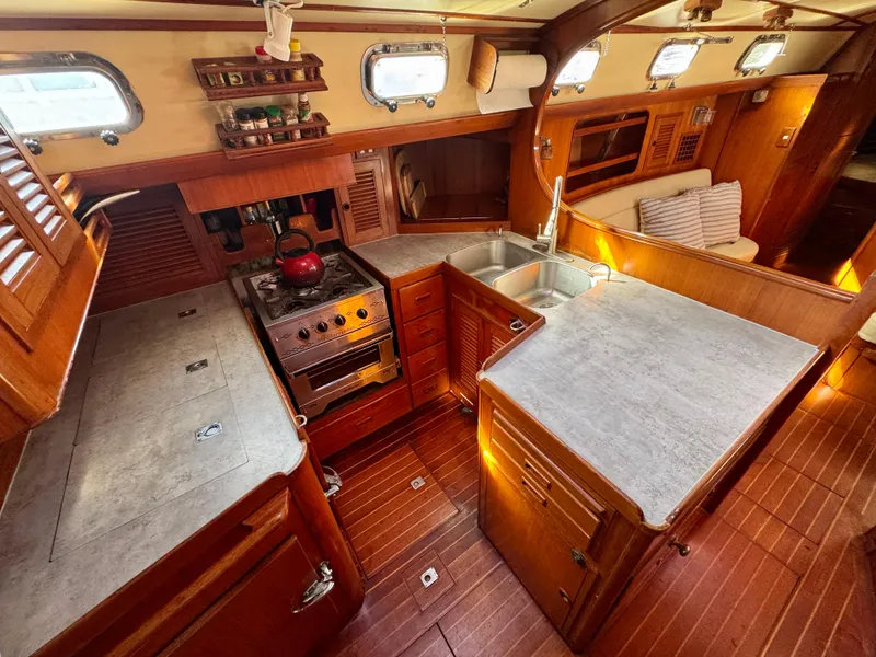 Slide: The Image of 1983 Tayana 52 Aft Cockpit yacht interior with wooden cabinetry and modern kitchen amenities. - 8
