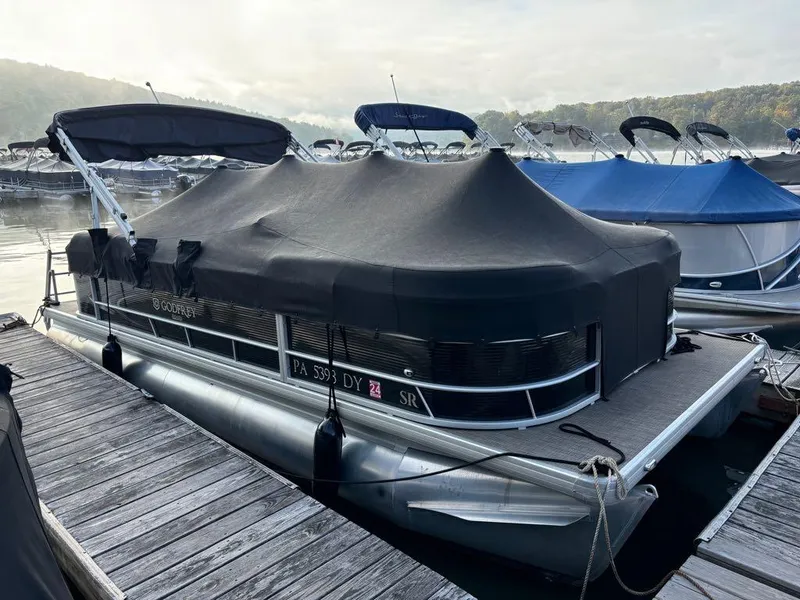Slide: The Image of 2020 Sweetwater SW 2186 SB pontoon boat docked with cover on, calm lake background. - 14
