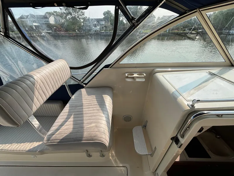 Slide: The Image of 2005 Mainship Pilot 30-II Sedan interior with river view, featuring seating and helm area. - 24