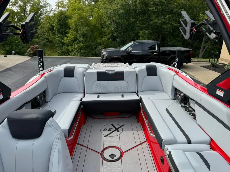 Slide: The Image of 2022 MasterCraft X24 boat interior with gray seating and red accents, parked near a black truck. - 12
