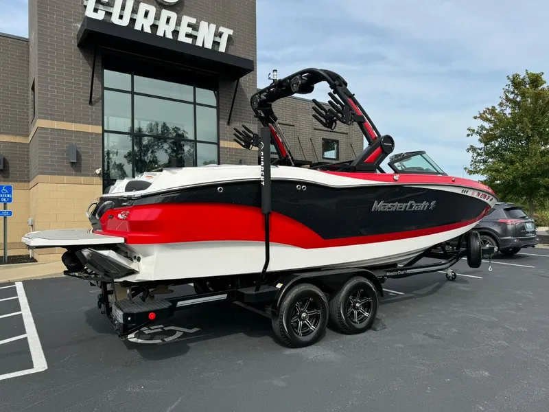 Slide: The Image of 2022 MasterCraft X24 boat on trailer, parked outside a building. - 3