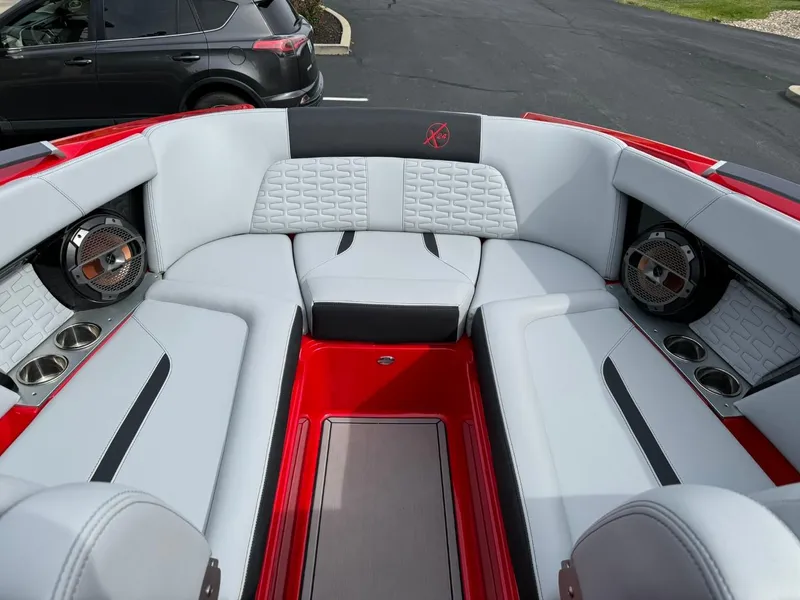 Slide: The Image of 2022 MasterCraft X24 boat interior with red and gray seating, speakers, and cup holders. - 9